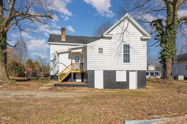 back of house featuring brick siding and a chimney