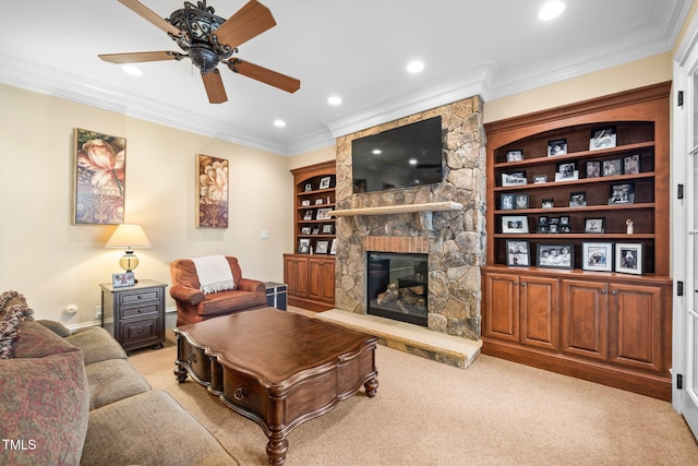 carpeted living room with built in shelves, ceiling fan, ornamental molding, and a stone fireplace