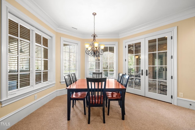 dining room featuring ornamental molding, light colored carpet, a chandelier, and french doors