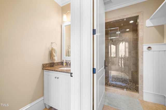 bathroom with a shower with door, vanity, tile patterned flooring, and crown molding