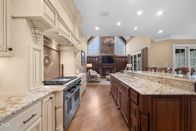 kitchen with sink, high end range, ornamental molding, a kitchen breakfast bar, and cream cabinetry