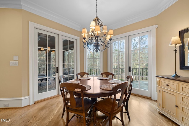 dining space with crown molding, a notable chandelier, light wood-type flooring, and french doors