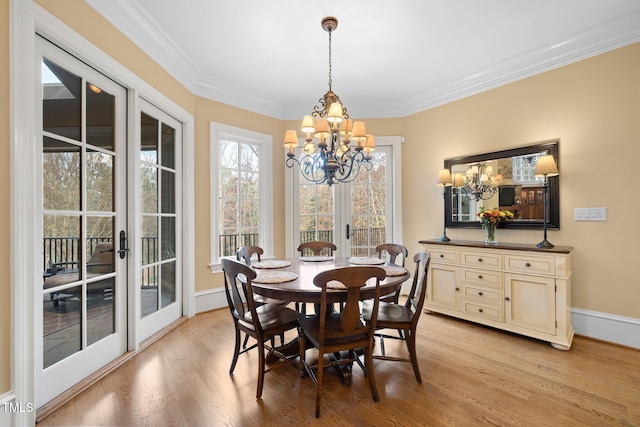 dining space featuring crown molding, a notable chandelier, light hardwood / wood-style floors, and french doors