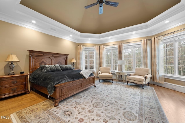 bedroom featuring crown molding, light hardwood / wood-style flooring, a raised ceiling, and ceiling fan