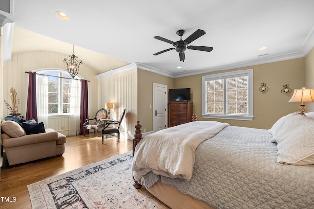 bedroom featuring ornamental molding, ceiling fan with notable chandelier, and hardwood / wood-style floors