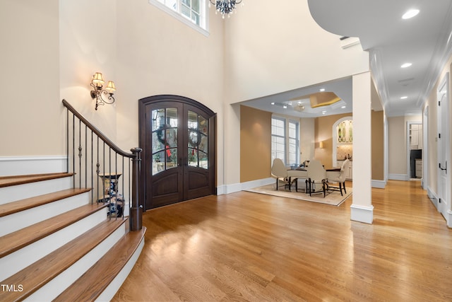 entrance foyer with ornamental molding, french doors, a healthy amount of sunlight, and light wood-type flooring