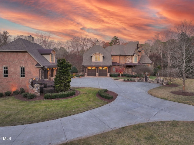 french country style house featuring a garage and a yard