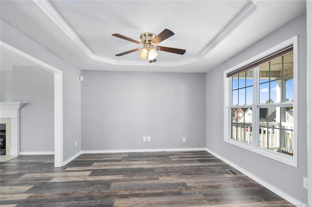 spare room with dark hardwood / wood-style floors, a fireplace, a raised ceiling, and crown molding