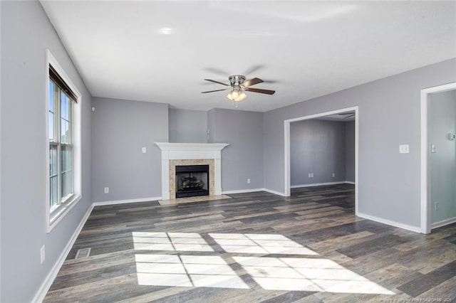 unfurnished living room with dark wood-type flooring, a tile fireplace, and ceiling fan