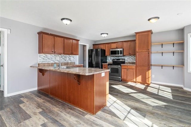 kitchen featuring a breakfast bar, sink, appliances with stainless steel finishes, kitchen peninsula, and backsplash