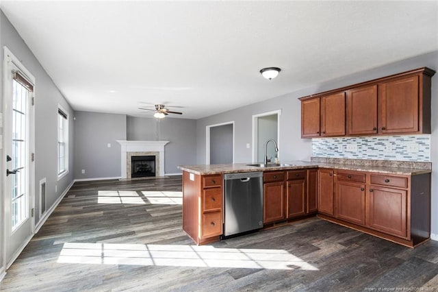 kitchen with tasteful backsplash, sink, dark hardwood / wood-style flooring, stainless steel dishwasher, and kitchen peninsula