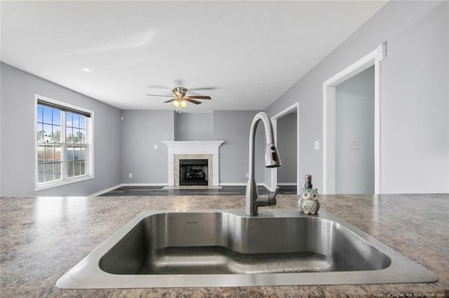 kitchen with ceiling fan, sink, and a fireplace