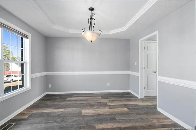 spare room with ornamental molding, dark hardwood / wood-style flooring, and a tray ceiling