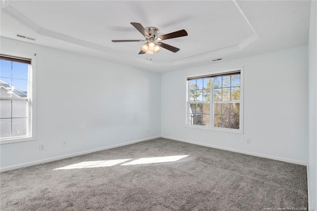 carpeted spare room with ceiling fan and a raised ceiling