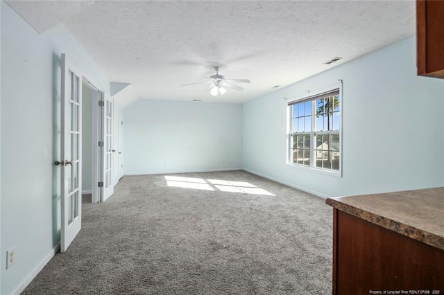 carpeted spare room with ceiling fan, a textured ceiling, and french doors