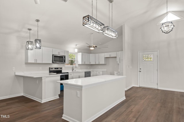 kitchen with stainless steel appliances, decorative light fixtures, kitchen peninsula, and white cabinets