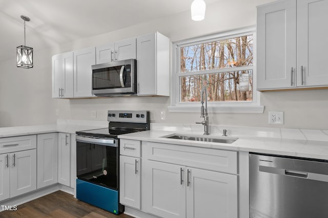 kitchen with decorative light fixtures, sink, white cabinets, dark hardwood / wood-style flooring, and stainless steel appliances