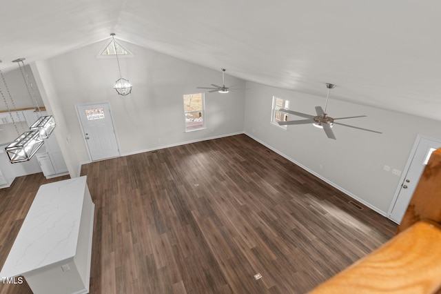 unfurnished living room featuring dark wood-type flooring, high vaulted ceiling, and ceiling fan with notable chandelier