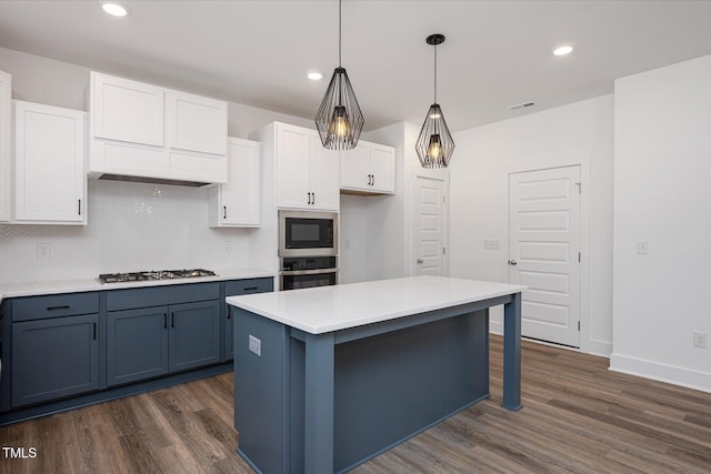 kitchen featuring appliances with stainless steel finishes, decorative light fixtures, white cabinetry, a center island, and dark wood-type flooring