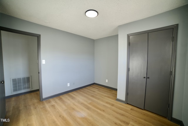 unfurnished bedroom featuring a closet, a textured ceiling, and light wood-type flooring