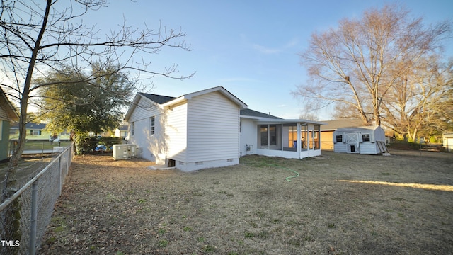 back of house featuring a sunroom, a yard, and a storage shed