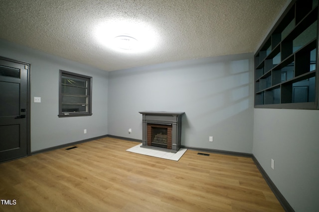 interior space with hardwood / wood-style floors, a brick fireplace, and a textured ceiling