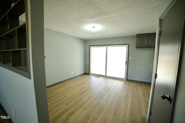 spare room featuring light hardwood / wood-style flooring and a textured ceiling