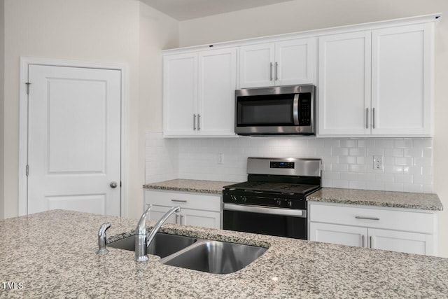 kitchen with sink, white cabinetry, light stone counters, tasteful backsplash, and stainless steel appliances