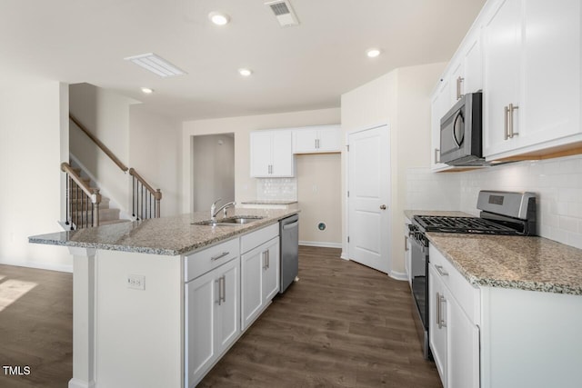 kitchen featuring sink, light stone counters, appliances with stainless steel finishes, a kitchen island with sink, and white cabinets