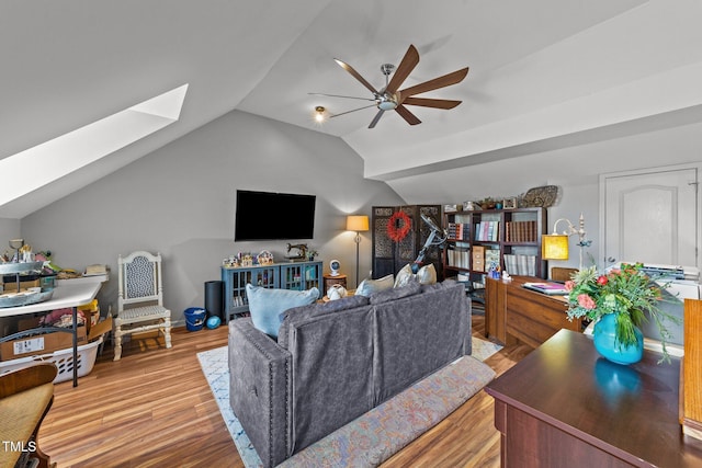 living room with vaulted ceiling with skylight, ceiling fan, and light hardwood / wood-style flooring