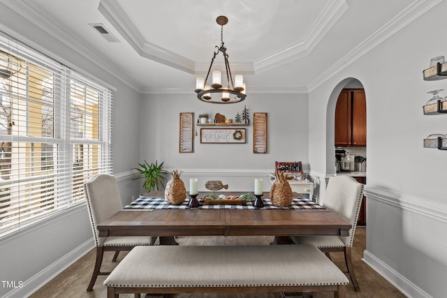 dining area featuring a notable chandelier, a tray ceiling, and ornamental molding