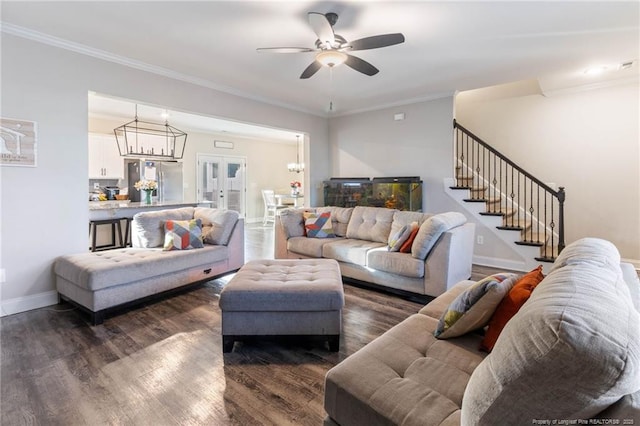 living room with dark wood-type flooring, ornamental molding, and ceiling fan with notable chandelier