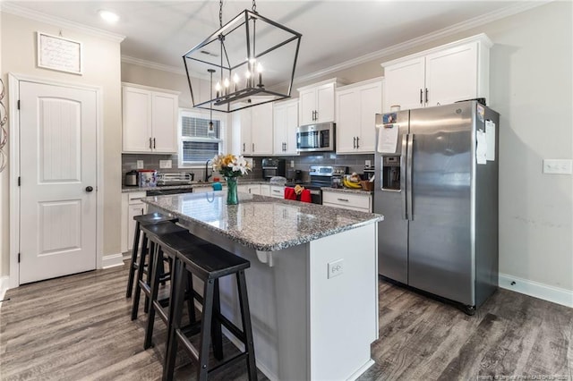 kitchen with stainless steel appliances, white cabinetry, a kitchen island, and backsplash