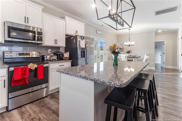 kitchen featuring hanging light fixtures, appliances with stainless steel finishes, a center island, and white cabinets