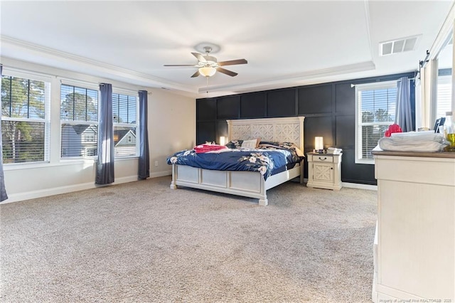 carpeted bedroom with a raised ceiling and ceiling fan