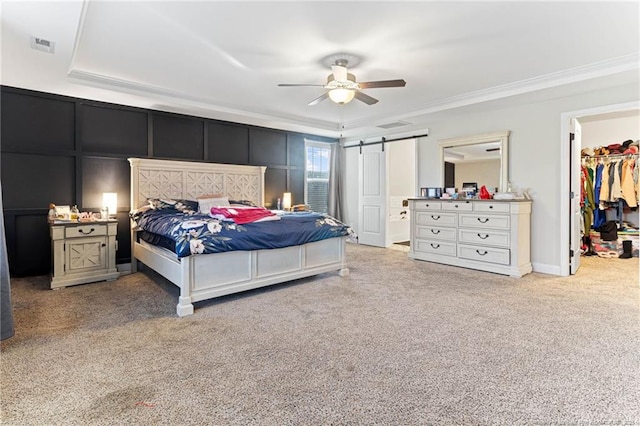 bedroom with a spacious closet, ceiling fan, a barn door, light carpet, and a closet