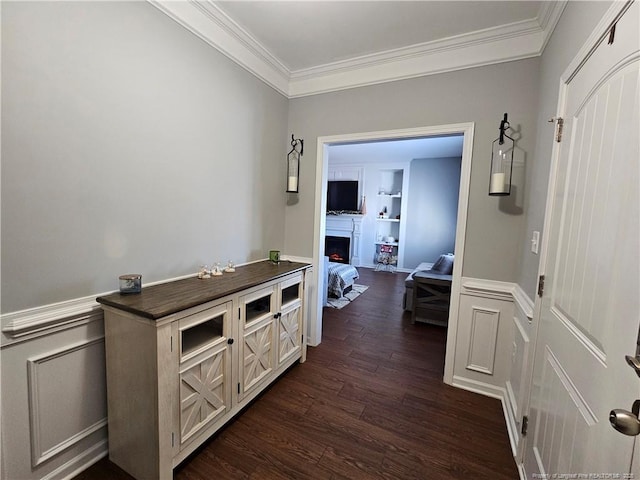 hallway with built in shelves, ornamental molding, and dark hardwood / wood-style flooring