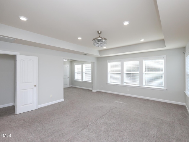 unfurnished room with a raised ceiling and light colored carpet