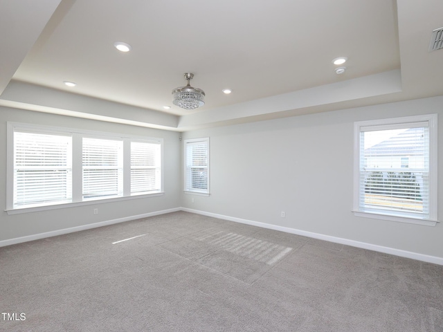 carpeted spare room featuring a tray ceiling