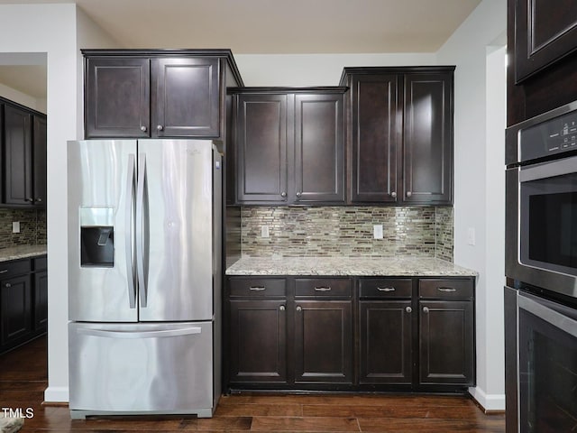 kitchen with dark hardwood / wood-style floors, decorative backsplash, light stone counters, stainless steel appliances, and dark brown cabinets