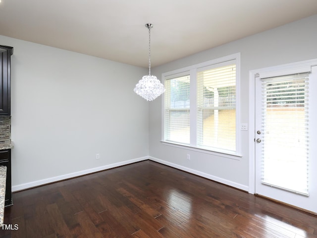 unfurnished dining area featuring dark wood-type flooring and a notable chandelier