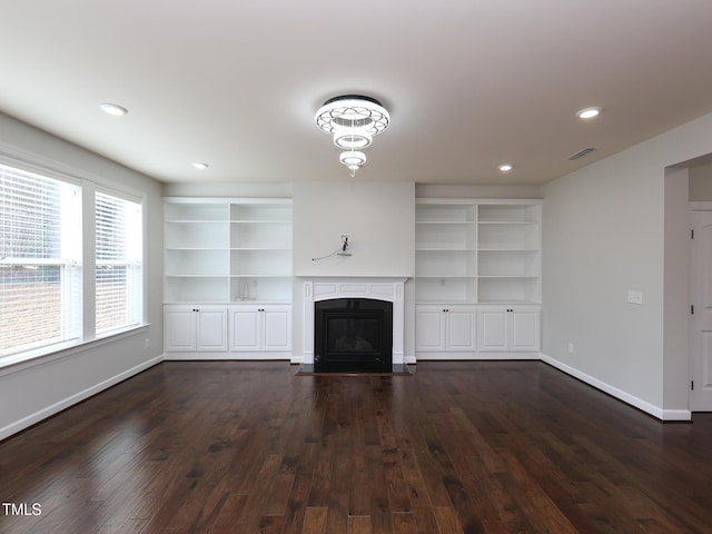 unfurnished living room featuring built in features and dark hardwood / wood-style flooring