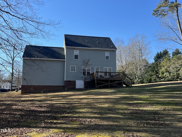 back of property featuring a wooden deck and a lawn