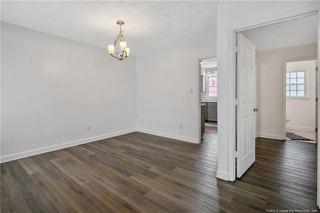 unfurnished room with a chandelier and dark hardwood / wood-style flooring