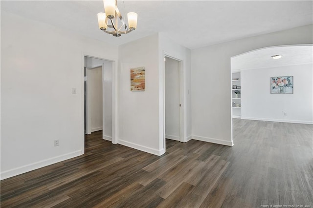 empty room with a notable chandelier and dark wood-type flooring