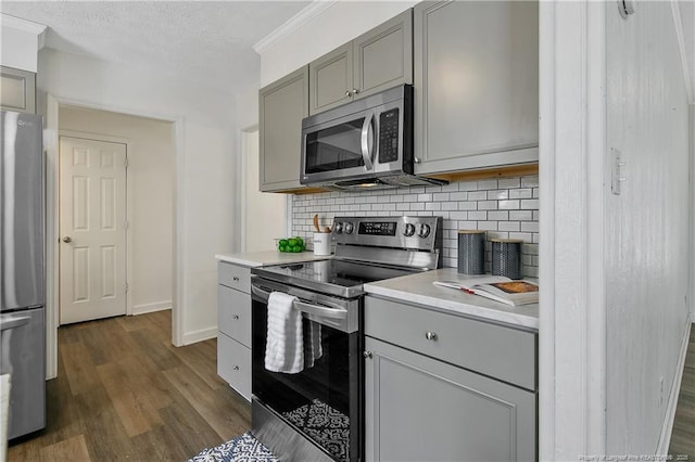 kitchen featuring gray cabinetry, tasteful backsplash, a textured ceiling, dark hardwood / wood-style floors, and stainless steel appliances