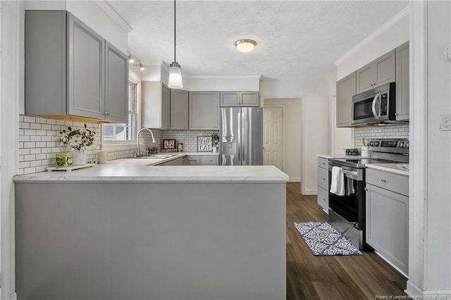 kitchen featuring appliances with stainless steel finishes, decorative light fixtures, kitchen peninsula, and sink