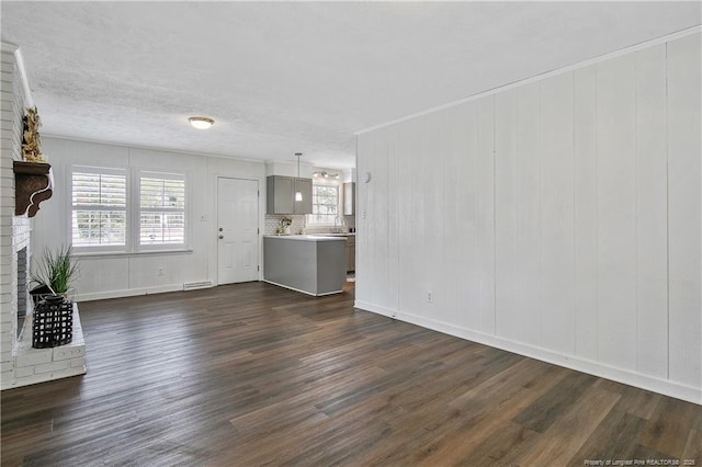 unfurnished living room with a fireplace, dark wood-type flooring, and ornamental molding