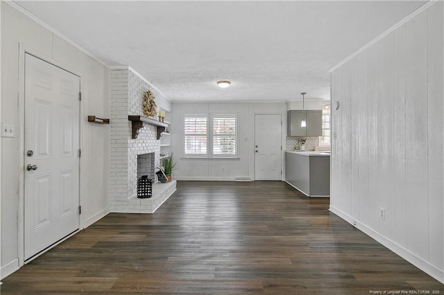 unfurnished living room featuring dark hardwood / wood-style floors, ornamental molding, and a fireplace