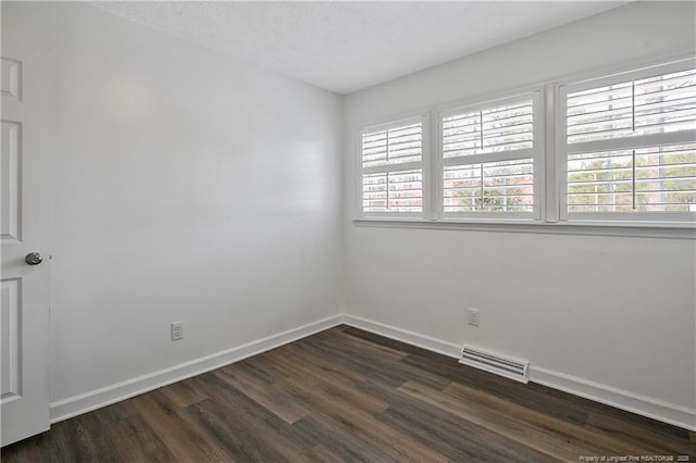 unfurnished room with dark hardwood / wood-style flooring and a textured ceiling